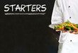 Chef with chalk starters sign on blackboard background