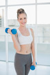 © lightwavemedia - Smiling athletic blonde exercising with dumbbells