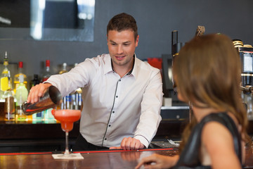 Handsome bartender serving cocktail to gorgeous woman