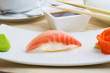 Grouper nigiri on white plate with soy sauce and chopsticks