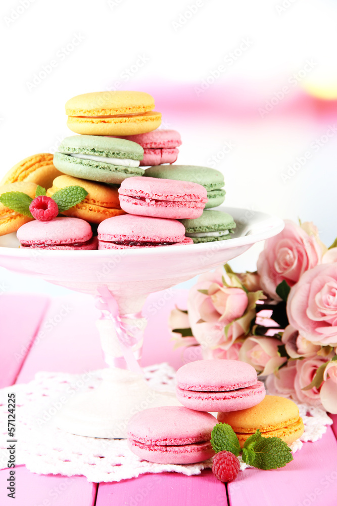 Gentle macaroons in vase on table on light background