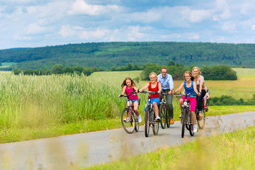 Family cycling in summer in rural landscape