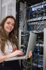 Woman happily using laptop to work on servers