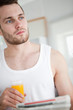 © WavebreakMediaMicro - Portrait of a good looking man drinking orange juice while readi