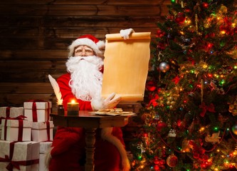 Santa Claus with gift boxes in wooden house interior