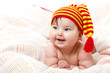 © Khorzhevska - cute baby lying on pink plaid and smiling in vivid funny hat, be