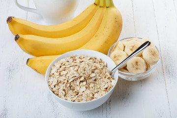 Bowl of oat flakes with sliced banana close-up on wooden table