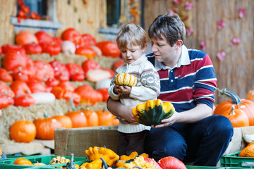 young father and his little son on pumpkin patch farm.