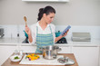 © lightwavemedia - Focused gorgeous woman wearing apron using tablet while cooking