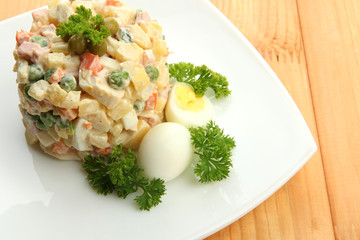 Russian traditional salad Olivier, on wooden background