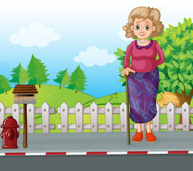 Wall Mural - An old woman with a cane standing at the roadside near the mailb