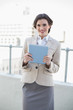 © lightwavemedia - Smiling stylish brown haired businesswoman holding a tablet pc