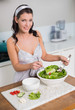 © lightwavemedia - Smiling pretty brunette mixing healthy salad