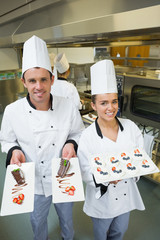 Wall Mural - Two young chefs presenting dessert plates