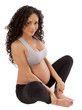 Very cute, small, pregnant woman sits in her workout clothing.