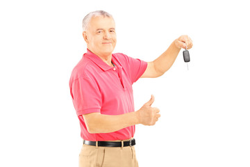 Wall Mural - Smiling senior man holding a car key and giving thumb up