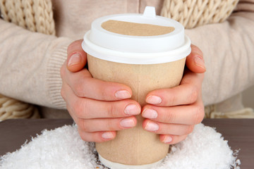 Poster - Hot drink in paper cup in hands with snow