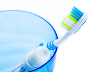 toothbrush and toothpaste in blue plastic glass