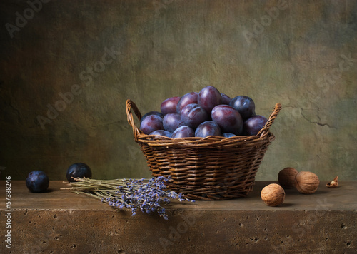 Fototapeta na wymiar Still life with black plums in a basket on the table