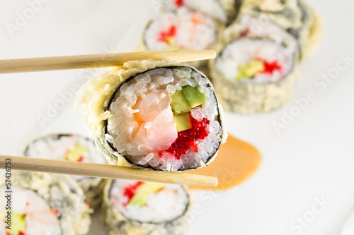 Board z aluminiowym obramowaniem Sushi roll w tempurze na białym talerzu i pałeczki