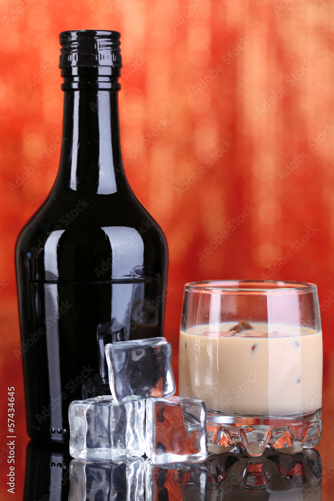 Baileys liqueur in bottle and glass on red background