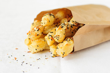 Puff pastry sticks with sesame seeds in a paper bag