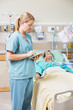 Nurse Using Digital Tablet While Patient Resting On Bed