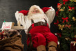 © Milles Studio - Santa Claus keeping his hands behind head while relaxing at home