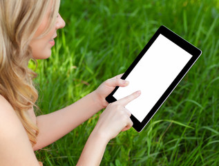 girl holds a tablet on a background of green grass