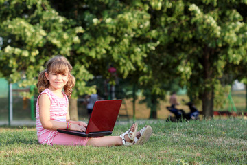 Wall Mural - beautiful little girl with laptop in park