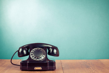 Retro black telephone on table in front mint green background