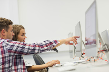 Two students working on computer pointing at it