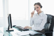© lightwavemedia - Focused beautiful agent wearing headset sitting at her desk