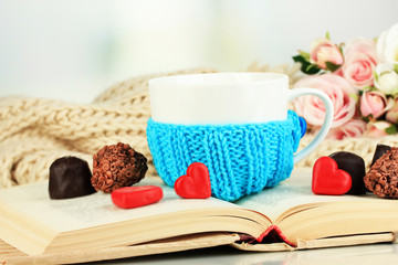 Wall Mural - cup with knitted thing on it and open book close up