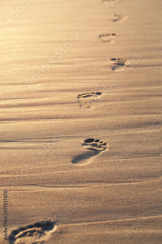 Obraz w ramie Close up of footprints on the beach sand at the sunset with copy