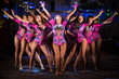 Nine showgirls in costumes with raised hands perform