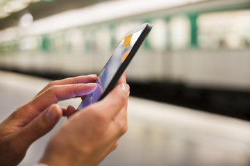 Wall Mural - Woman using her cell phone on subway platform