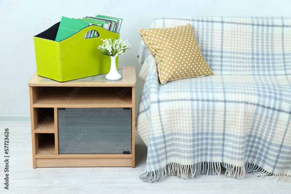 Magazines and folders in green box on bedside table in room
