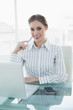 © lightwavemedia - Smiling chic businesswoman sitting at her desk in front of lapto