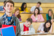 © WavebreakMediaMicro - Smiling male with students sitting at lecture hall
