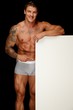 © Nejron Photo - Man with athletic muscular body holding blank notice board