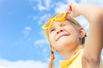 Wall Mural - portrait of a happy girl with sunglasses against the sky