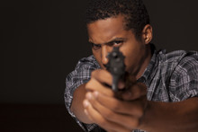 Dark-skinned Young Man Aiming With His Gun At You
