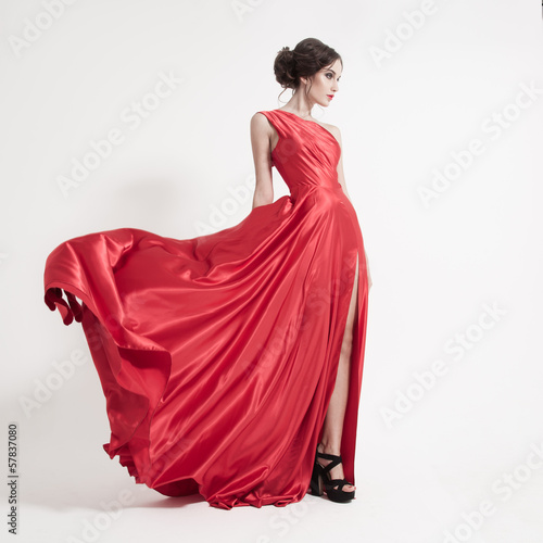 Fotografia, Obraz Young beauty woman in fluttering red dress. White background.
