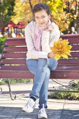 Wall Mural - girl sitting on a bench in autumn