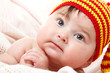 © Khorzhevska - cute baby lying on pink plaid and smiling in vivid funny hat, be
