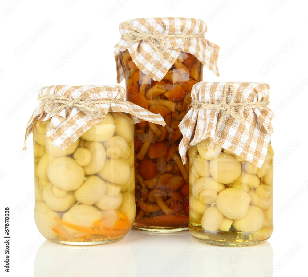 Delicious marinated mushrooms in glass jars, isolated on white