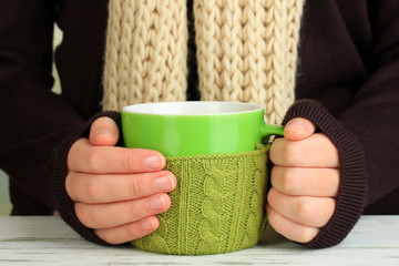 Aufkleber - Cup with knitted thing on it in female hands close up