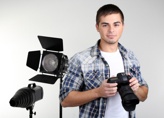 Handsome photographer with camera, on photo studio background