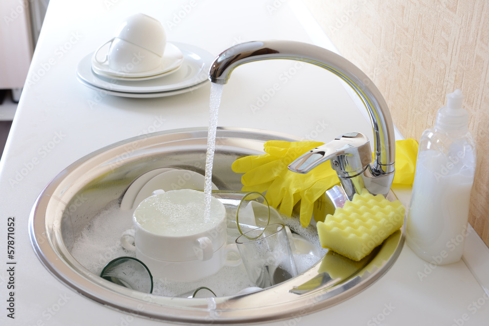 Stack of dishes soaking in kitchen sink
